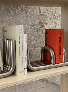 two books are sitting on a shelf next to some metal bookends with orange books