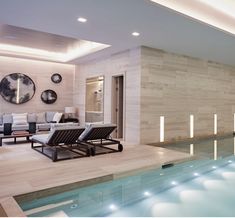 an indoor swimming pool with chaise lounges and mirrors on the wall behind it