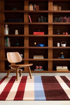 a wooden chair sitting on top of a rug in front of a bookshelf