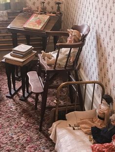 an old fashioned doll house with dolls on the floor and in chairs, next to a desk