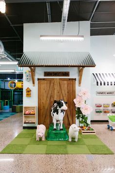 two fake cows on display in front of a wooden door and green carpeted area