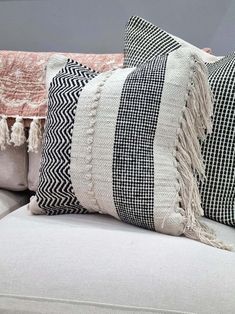 three pillows sitting on top of a couch with tassels and pom poms