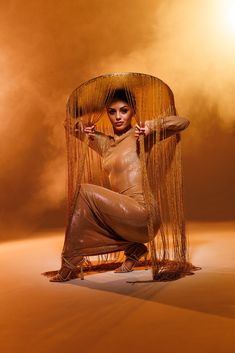 a woman is sitting on the floor with her legs spread out and holding a large object over her head