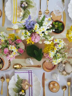 the table is set with flowers and place settings for an easter brunch party