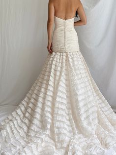 a woman in a white dress is standing on a white background with her back to the camera