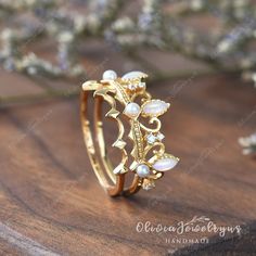 a gold ring with pearls and leaves on the inside, sitting on a wooden surface