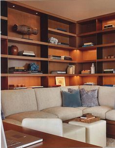 a living room filled with furniture and bookshelves next to a laptop on a table