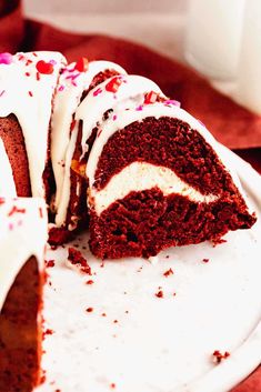 a piece of red velvet cake with white frosting and sprinkles on a plate