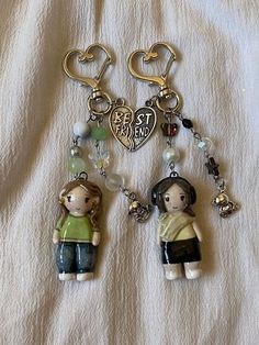 two key chains with charms attached to them sitting on a bed next to each other