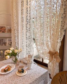 the table is set with tea and pastries for two people to enjoy in front of the window