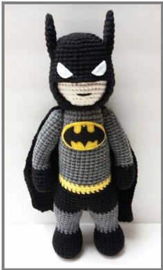 a crocheted batman stuffed animal is posed on a white surface with its eyes open