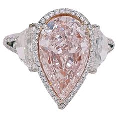 Absolutely stunning engagement ring style showcasing a Fancy Light Pink 3.25 carat pear-shaped diamond certified by GIA as VS2 clarity. The center stone surrounded by a round brilliant white diamonds halo, Flanked by two Cadillac cut diamonds total weight 1.29 ct. SI1 clarity, E color. Set in a polished 18K white gold. Total diamonds weight: 5.27 carat. This piece was handmade at the Novel Collection Jewelry Atelier, which specializes in rare collectible pieces in the Fancy color diamond. For many jewelry lovers, a fancy pink diamond represents the Platonic ideal. They combine the diamond's significant hardness and brilliance with a spectacular uniqueness found nowhere else on earth, embodying three key attributes: hardness (ranking 10 on the Mohs scale), rarity, and beauty. When the Argyl Pink Cushion Cut Engagement Ring, Jewelry Atelier, Pink Diamonds Engagement, Engagement Ring Style, Pink Diamond Engagement Ring, Fancy Light, Pink Diamond Ring, Pink Diamonds, Stunning Engagement Ring