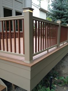 a wooden deck with railings in front of a house