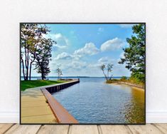 a framed photograph of a lake with trees on the side and water in the foreground