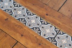 a wooden floor with an intricate design on the top and bottom part, in grey and white colors