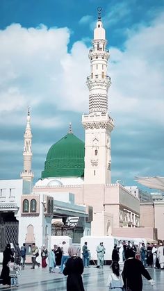 many people are walking around in front of a large white building with a green dome