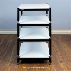 three black and white shelving units sitting on top of a hard wood floor