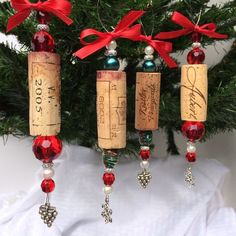 three wine corks are hanging from a christmas tree with red ribbon and bows on them