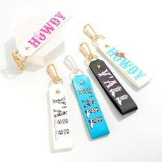 four key chains with different designs on them sitting in front of a white box that says happy birthday