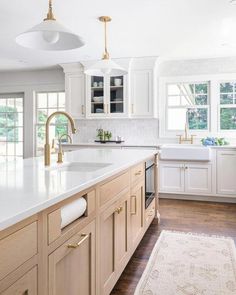 a large kitchen with white cabinets and gold hardware on the countertops, along with an area rug that matches the hardwood flooring