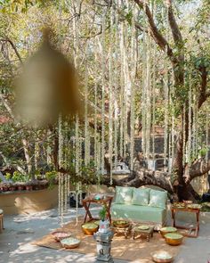 an outdoor living area with couches, tables and potted plants on the ground