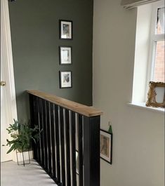 a staircase with pictures on the wall above it and a plant in front of an open window