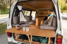 the back end of a van with two couches and coffee mugs in it