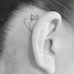 a woman's ear with a small cat tattoo on it