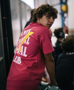 a man in a red shirt standing next to a wall