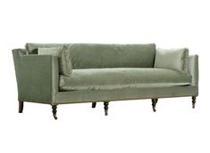 a green velvet couch with wooden legs and pillows on the back, against a white background