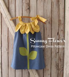 a blue dress with yellow flowers hanging on a wooden wall and the words sunny flower pillowcase dress pattern