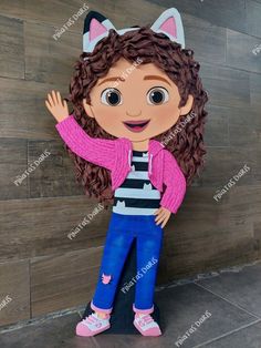 the girl with long hair is standing in front of a wooden wall wearing a pink sweater and blue jeans