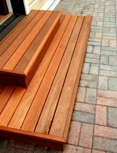 a wooden bench sitting on the side of a brick road next to a door and window