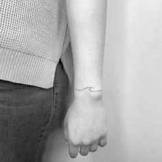 a woman's arm with a small wave tattoo on it