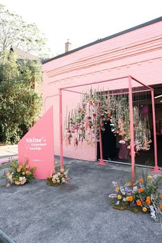 a pink building with flowers hanging from it's sides and a sign in front