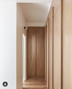 an empty hallway with wooden cabinets and wood flooring on both sides is seen in this image