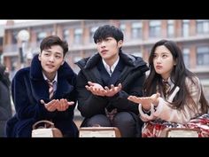 three young people sitting on the ground with their hands out in front of them,