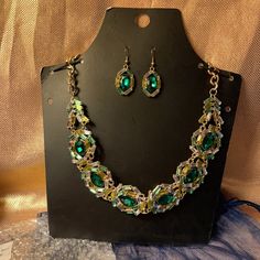 Beautiful Necklace Set With Matching Earrings. Large Green Jewel In The Middle With Yellow And Clear Jewels Around The Large Green Stone With Gold Colored Chain. Necklace Has Extender Chain And Earrings Are On Fish Hooks. Brand New In Package. Comes With Blue Tie Bag. Nice Set For A Christmas Gift. Formal Green Jeweled Jewelry Sets, Green Crystal Jewelry With Matching Earrings, Green Metal Necklaces With Matching Earrings, Green Metal Jewelry For Formal Occasions, Green Crystal Jewelry For Party, Formal Green Metal Jewelry, Green Crystal Jewelry With Jeweled Details, Green Metal Jewelry For Party, Green Metal Jewelry For Parties