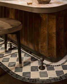 an old fashioned bar with two stools and a bowl of fruit on the counter