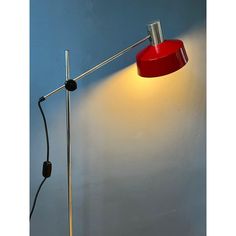 a red floor lamp on a blue wall