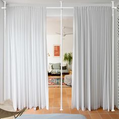 a living room with white curtains and a rug