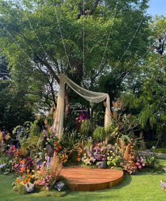 an outdoor garden with flowers, trees and a wooden platform in the middle of it