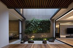 an indoor living area with wood flooring and green plants on the wall above it