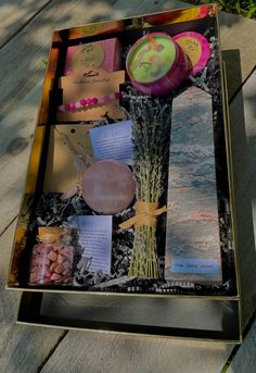 a box filled with assorted items sitting on top of a wooden table next to a tree