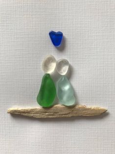 three sea glass pieces sitting on top of a piece of driftwood