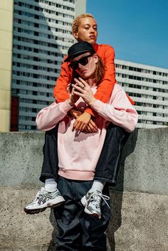 a woman sitting on top of a skateboard next to a man with his arms around her