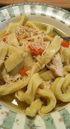 a bowl filled with chicken noodle soup on top of a green and white plate