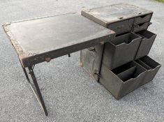 an old wooden desk with drawers on the top and bottom, sitting in graveled area