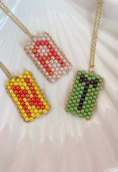 three pieces of beaded necklaces on a white surface, one with an arrow in the middle