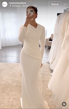 a woman taking a selfie in front of her wedding gowns on the phone